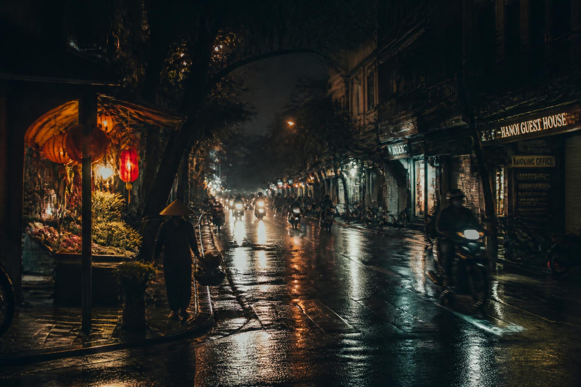 Hanoi old quarter at night in the rain, motorbike lights on wet streets